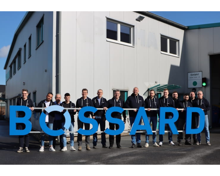 Gruppe von Menschen mit BOSSAARD-Logo vor einem Firmengebäude.