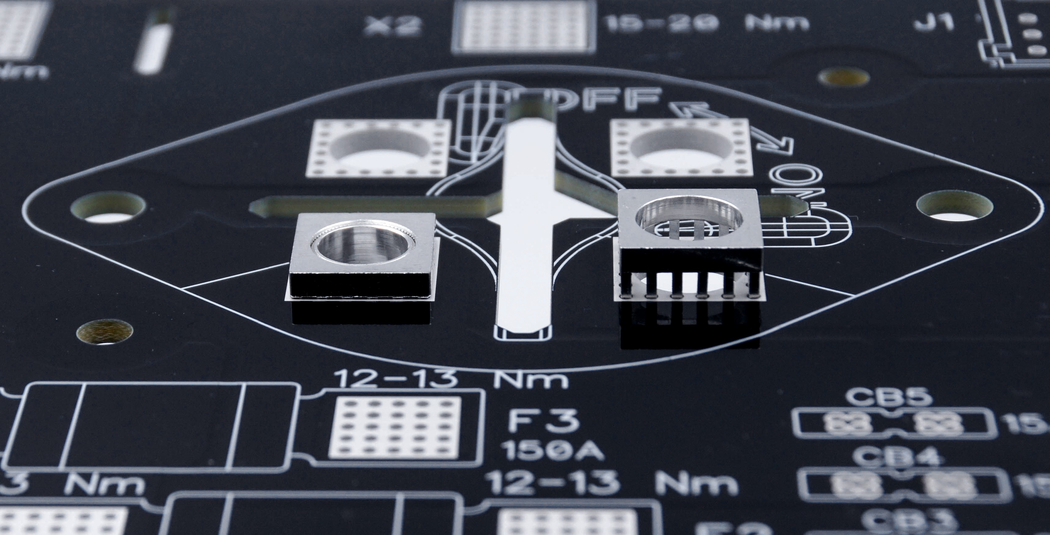 Gros plan d'un PCB noir avec des éléments d'alimentation MTCON, trois déjà pressés, un encore à assembler