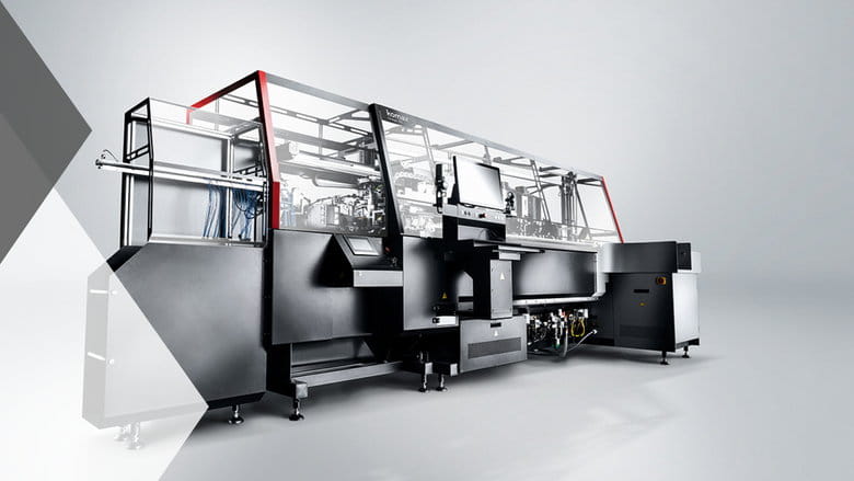 Große Industriemaschine mit elegantem schwarz-silbernem Design, ausgestattet mit einem Bildschirm und roten Akzenten, auf grauem Hintergrund.