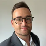 Porträt von Marc Hennings, lächelnder Mann im Anzug