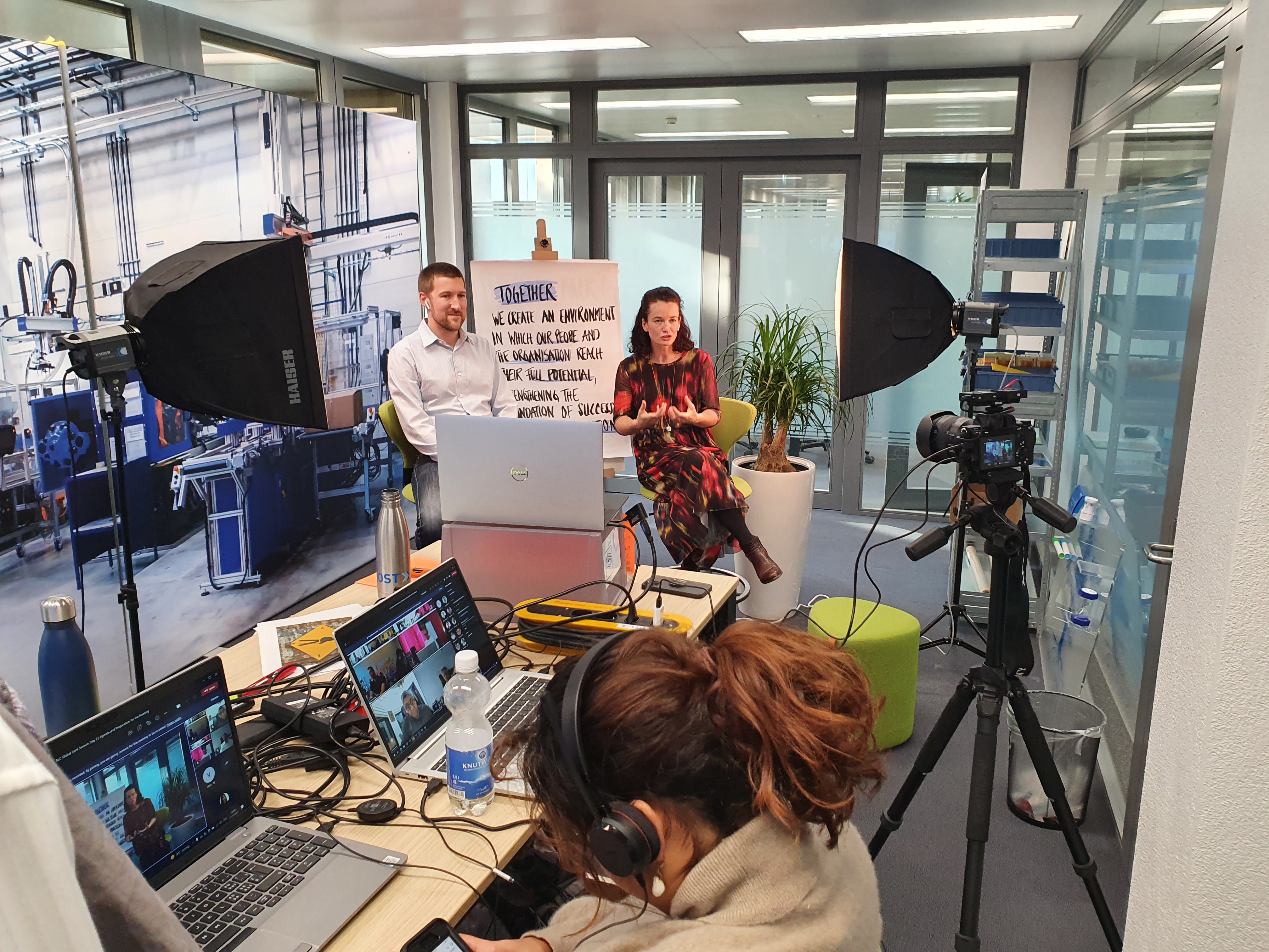 Egy csoport laptopokon dolgozó egyén a Bossard videófelvételi stúdiójában egy aktív felvételi munkamenet során.