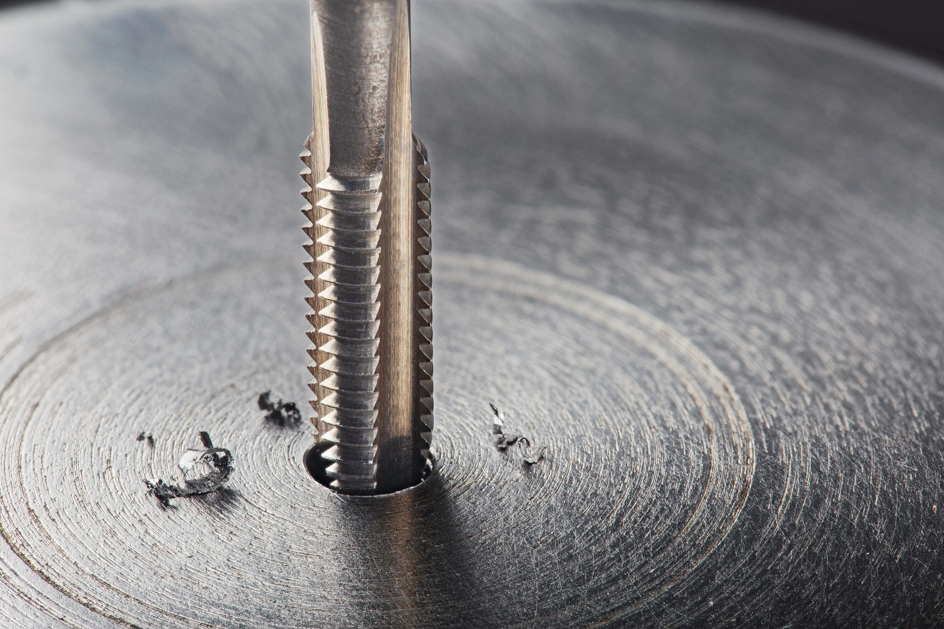 
Macho de roscar que perfora una superficie metálica.