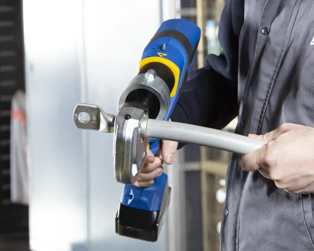 mand installerer kabelsko med et hydraulisk krympeværktøj