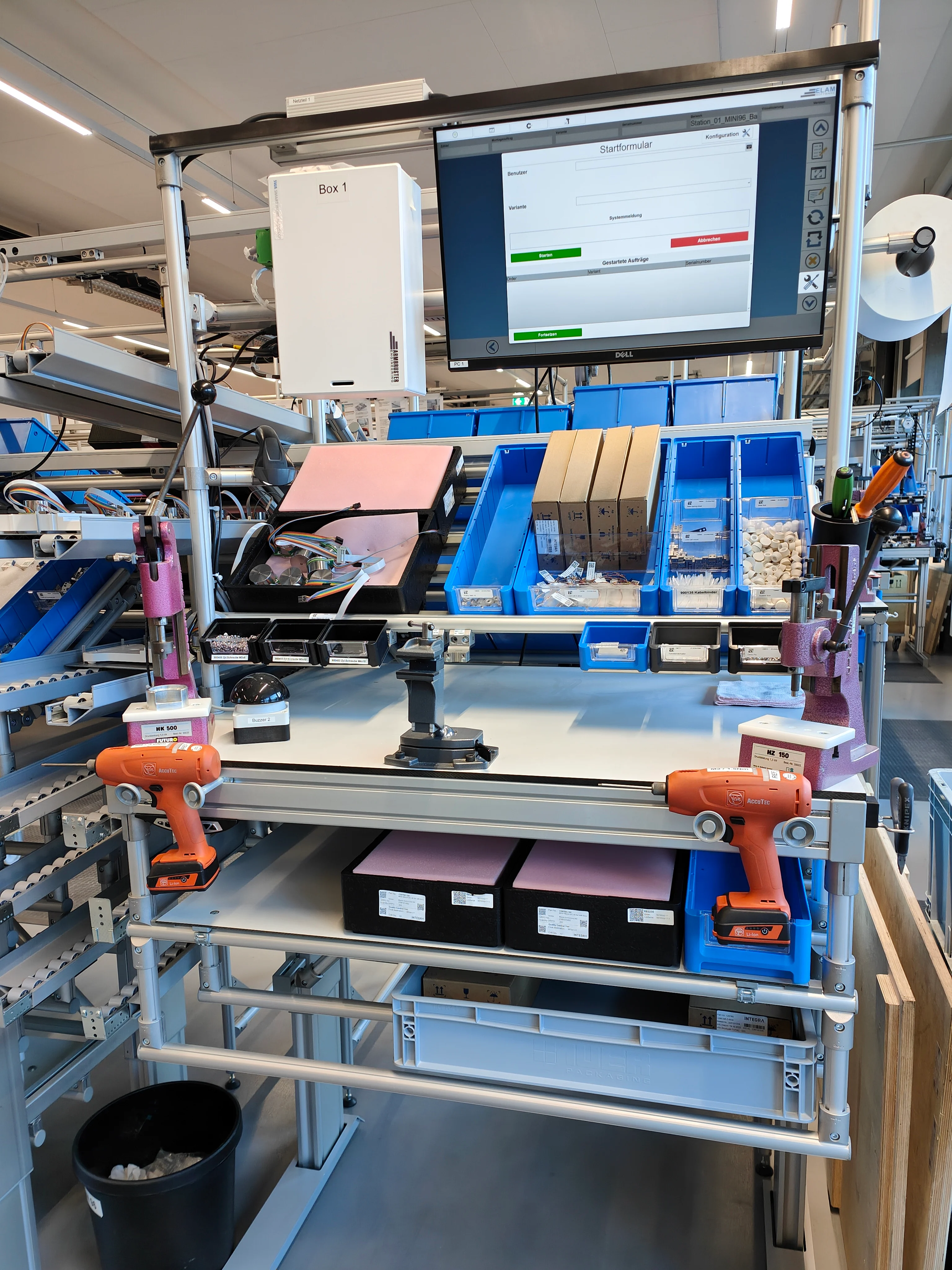 Ein Computerbildschirm auf einem Tisch in einer modernen Arbeitsstation mit Werkzeugen in einer Fabrik.