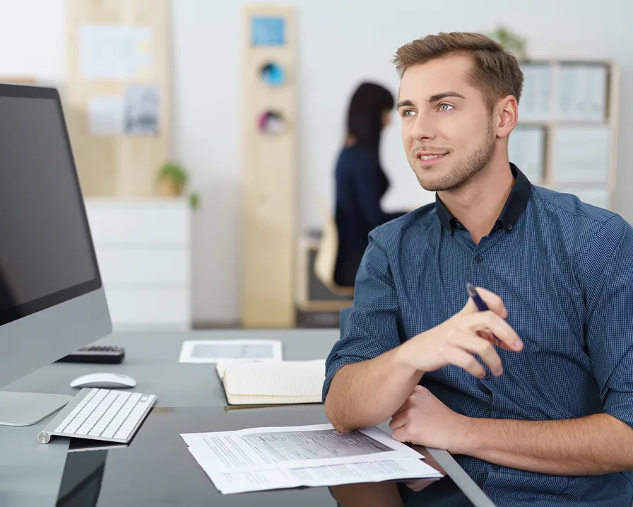 Man with a pen in his hand sitting at a desk
