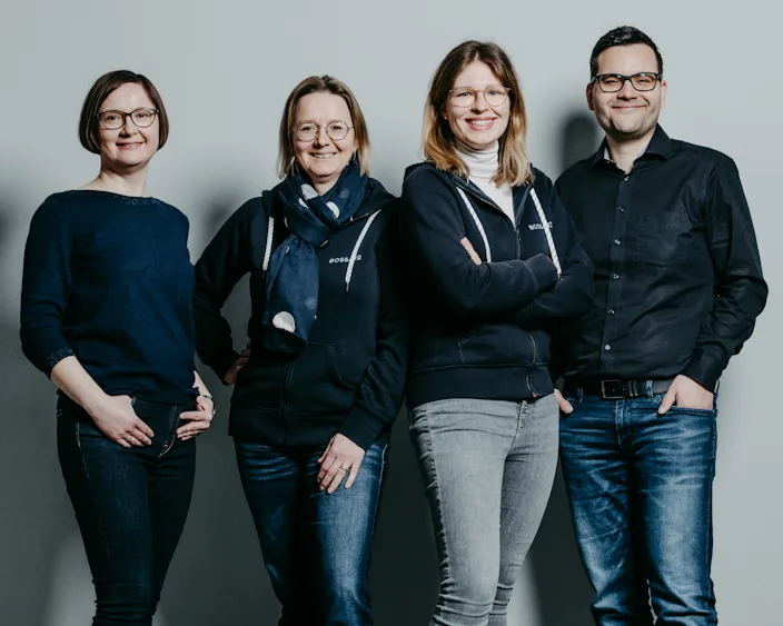 Vier Teammitglieder von Bossard Deutschland aus dem Bereich People & Organizational Development vor grauem Hintergrund.