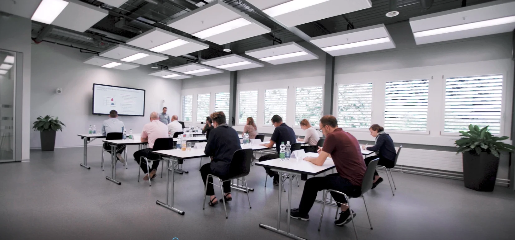 In einem Klassenzimmer sitzen Menschen an Tischen und beteiligen sich an einer gemeinsamen Diskussion.
