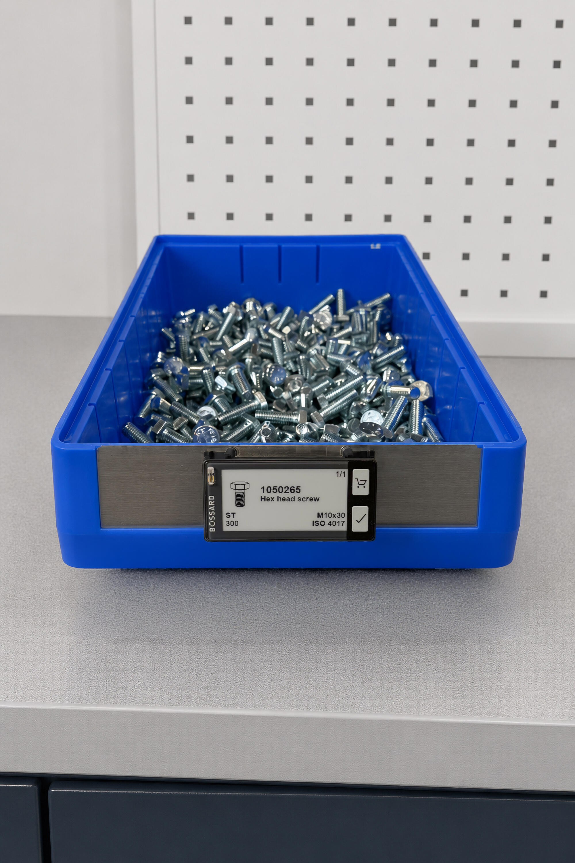 Bac de rangement en plastique bleu rempli de vis à tête hexagonale en métal, avec une étiquette intelligente indiquant le numéro de produit et la taille.