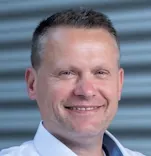 Portrait von Tobias Wolf mit blauem Hemd vor Metallhintergrund