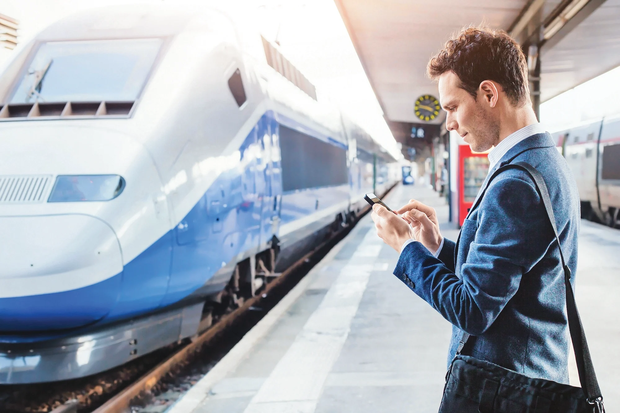 A man on a railway station using an electronic device
