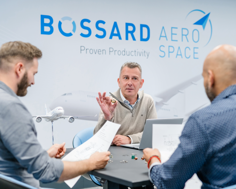 3 people reviewing design and fasteners with Bossard Aerospace wall background