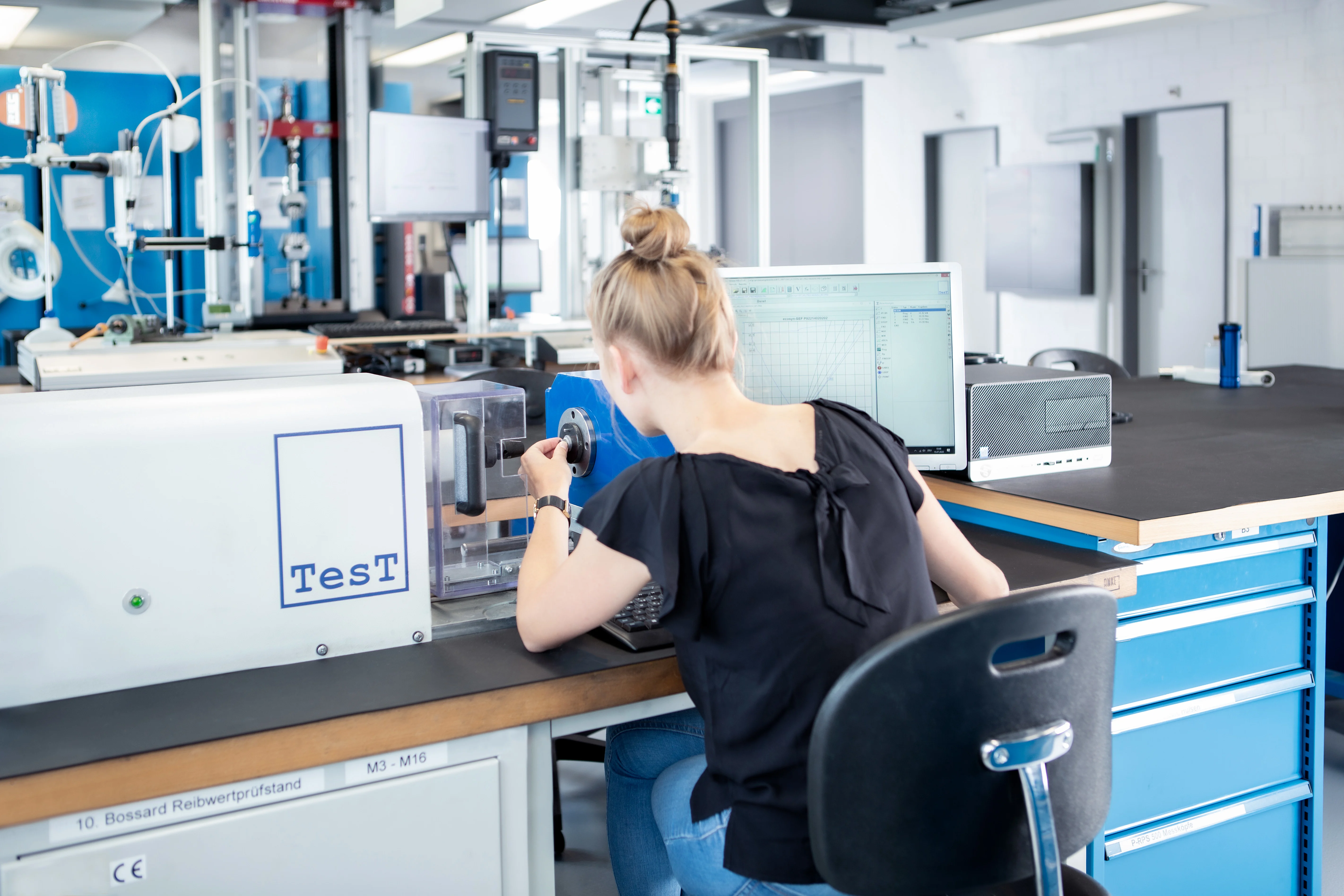 Person prepares a friction coefficient test at the desk in a technical testing laboratory.