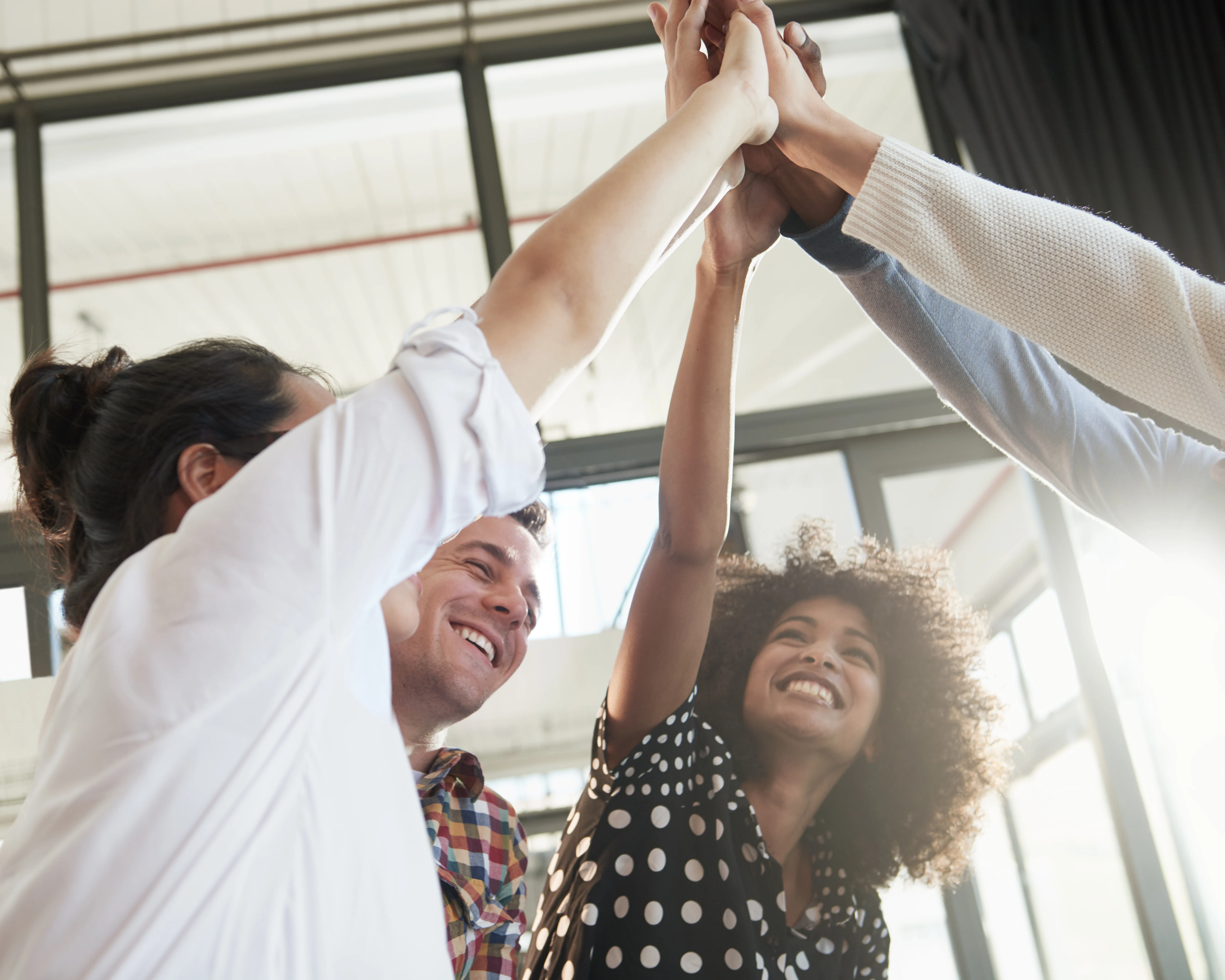 A group of people in an office giving each other high fives in the air.