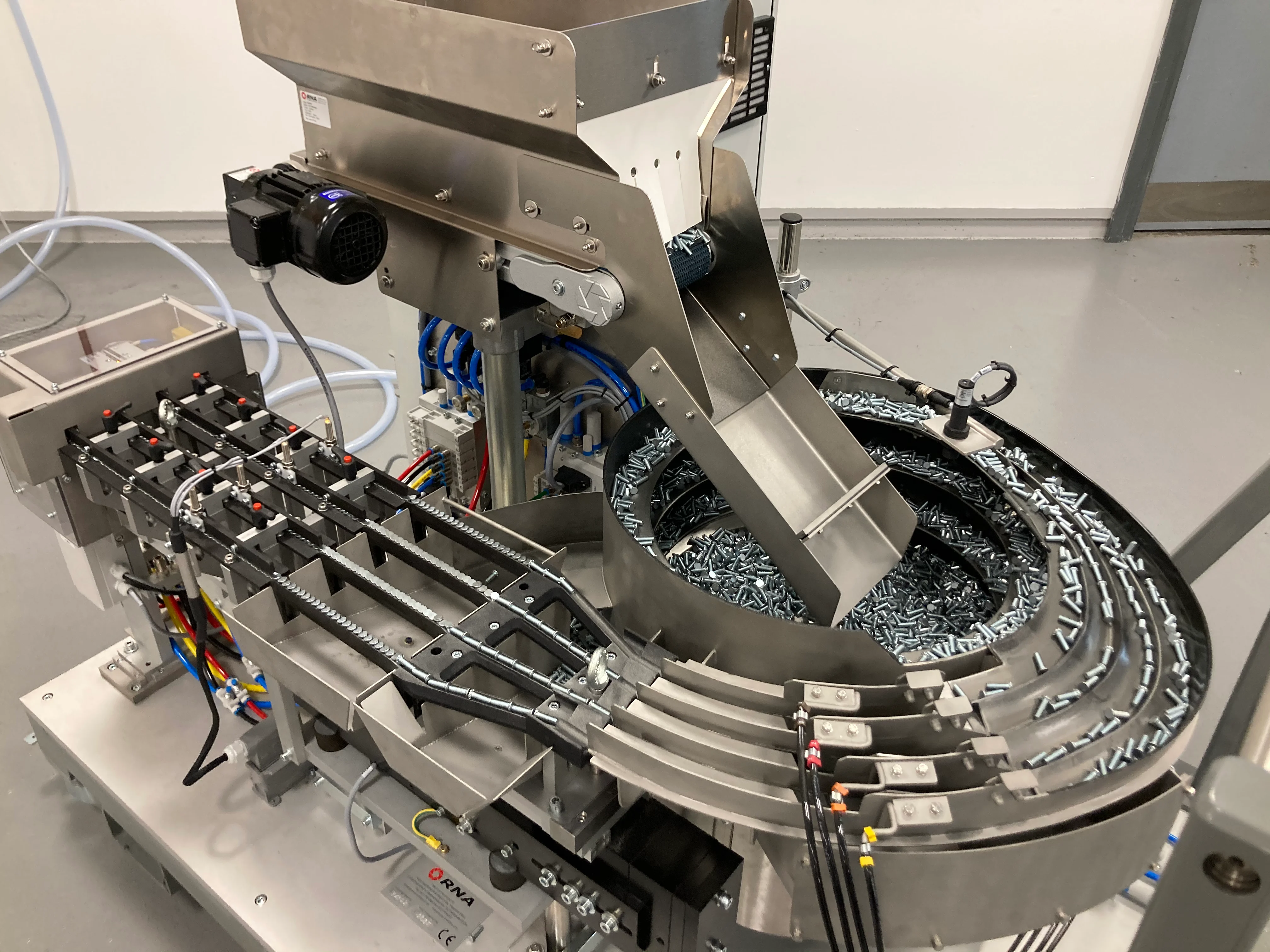 Primo piano della tramoggia, del sistema di alimentazione automatica e delle guide di alimentazione del carrello di alimentazione universale PEMSERTER IN-DIE NextGen.