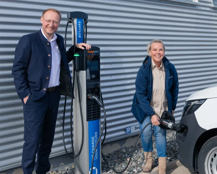 Geschäftsführer Daniel Stier und Mitarbeiterin an einer Bossard-Ladestation beim Laden eines Elektrofahrzeugs