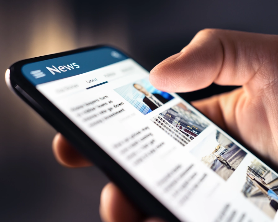 Nahaufnahme einer Hand, die auf einem Smartphone durch Online-Nachrichten scrollt