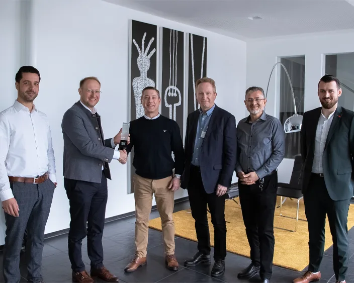 Fünf Geschäftsleute in einem modernen Büro, während einer Preisverleihung per Handschlag