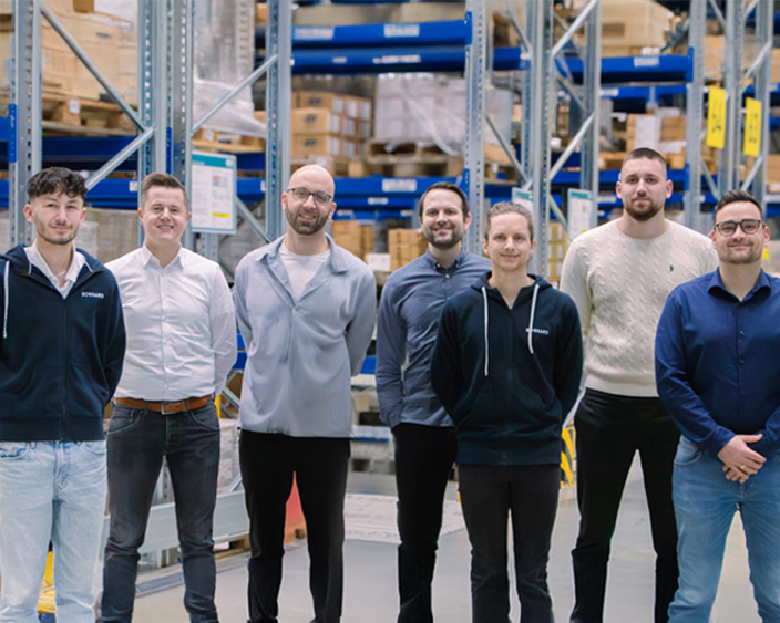 Kunststoff-Segment Team von steht in einem Lagergang vor vollen Regalen