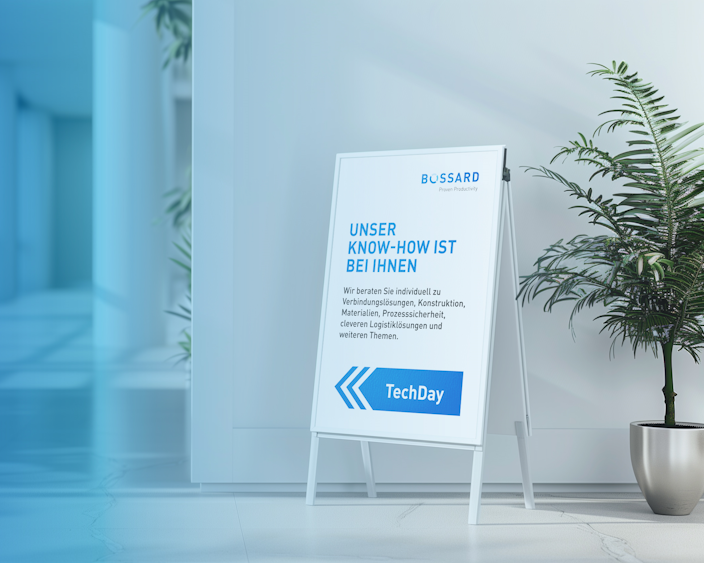 Aufsteller mit Bossard TechDay-Ankündigung in einem modernen, hellen Innenraum mit Pflanzen.
