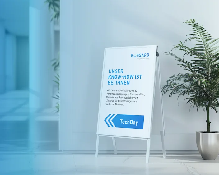 Aufsteller mit Bossard TechDay-Ankündigung in einem modernen, hellen Innenraum mit Pflanzen.