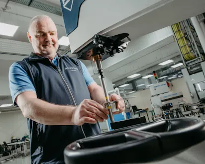 Bossard Experte arbeitet an einer Präzisionsmaschine in einer modernen Produktionsumgebung.