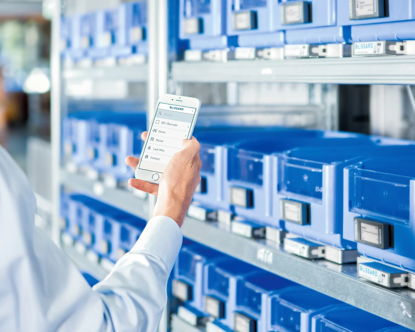 Người trên sàn sản xuất đang kiểm tra danh sách hàng tồn kho trên thiết bị di động.