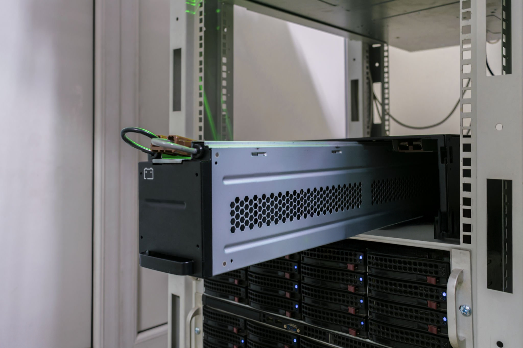 Equipos de servidor con hardware montado en rack negro y gris, rejillas de ventilación y luces LED azules en un armario de servidor blanco