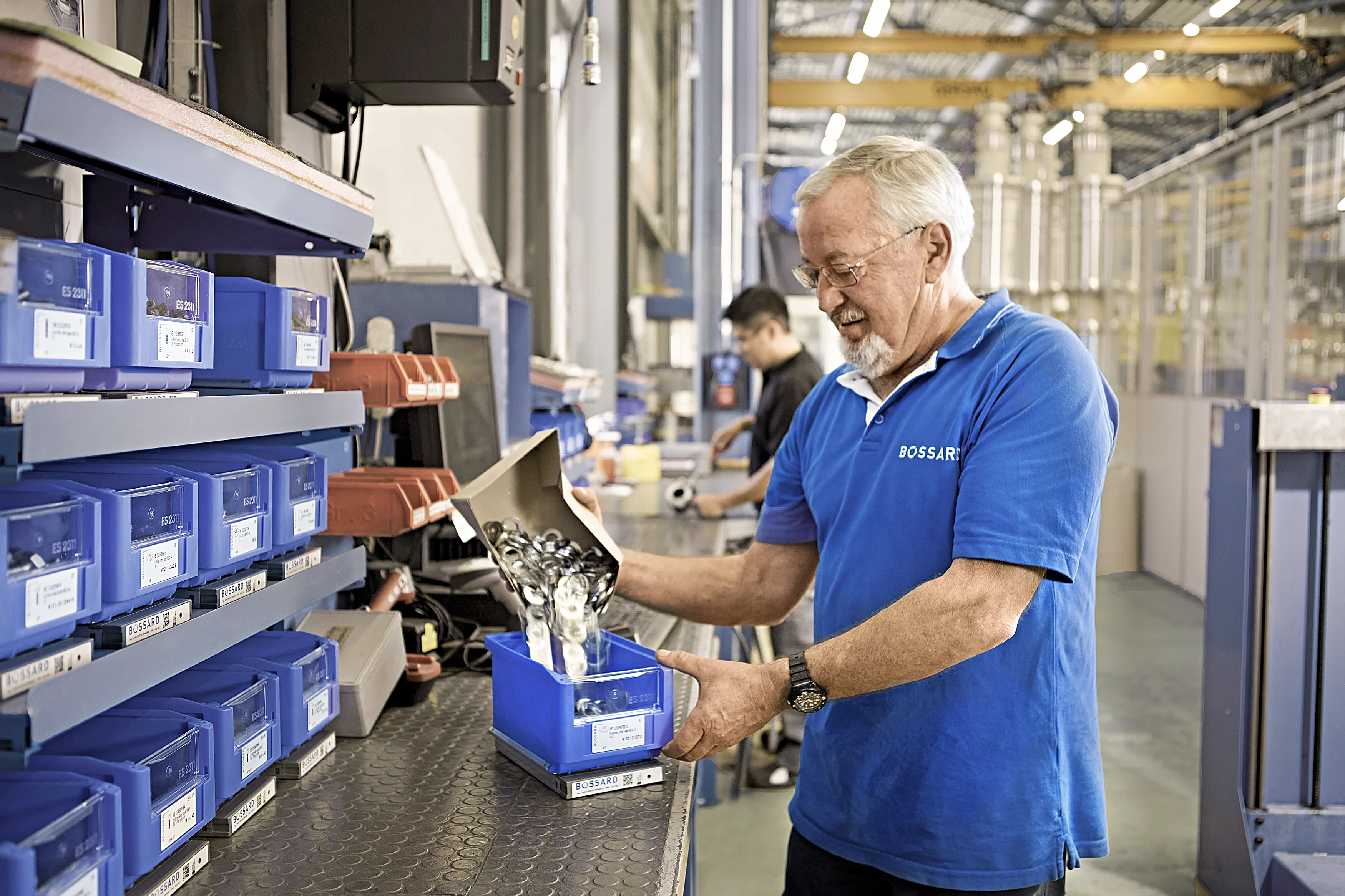 Bossard-medarbejder i blå skjorte genopfylder SmartBin-beholder på lagerlokation.