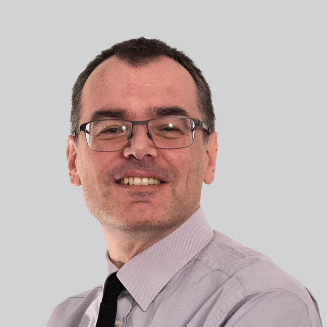 Ein Mann mit blauem Anzug lächelt freundlich in die Kamera.