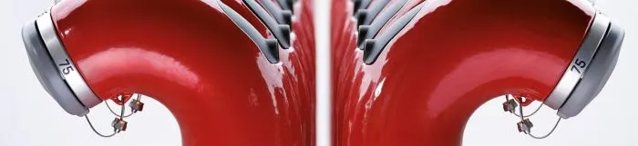 Deux rangées de bornes d'incendie rouges avec des capuchons argentés et des numéros, vues de côté, créant un motif symétrique.