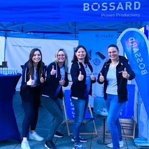 Vier lächelnde Frauen vor einem blauen Bossard-Zelt bei einer Veranstaltung