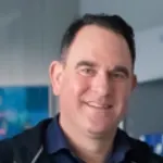 Portrait von Markus Mayer mit blauem Hemd vor Metallhintergrund