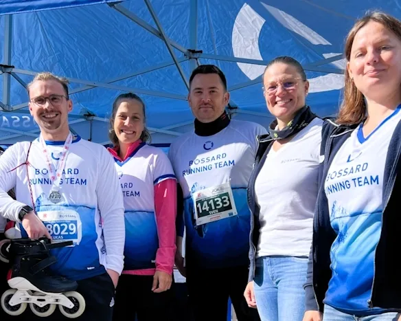 Strahlende Mitglieder des Bossard Running Teams in blauen und weißen Trikots bei einer Marathonveranstaltung
