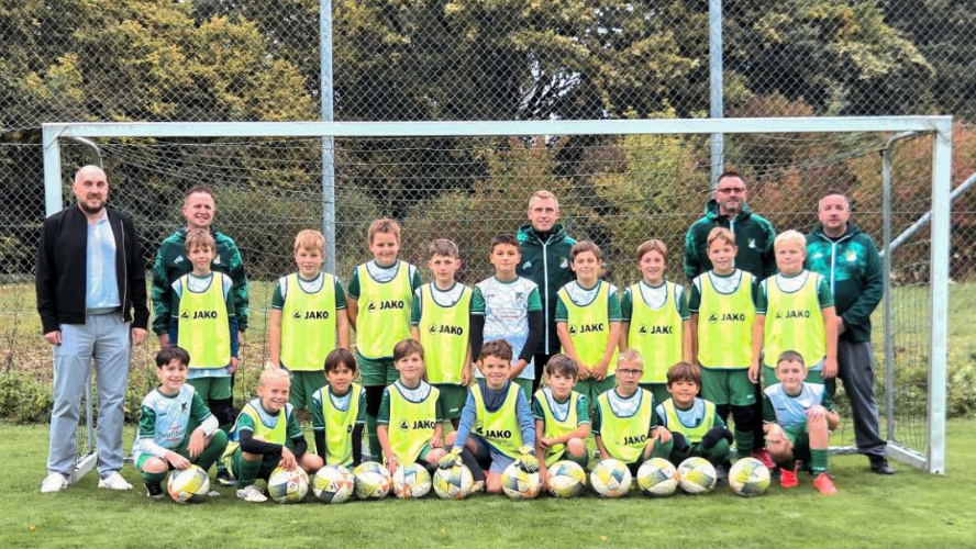 Jugendmannschaft des FV Schnürpflingen mit Trainern vor einem Fußballtor, ausgestattet mit neuen Fußbällen und Trainingsleibchen.