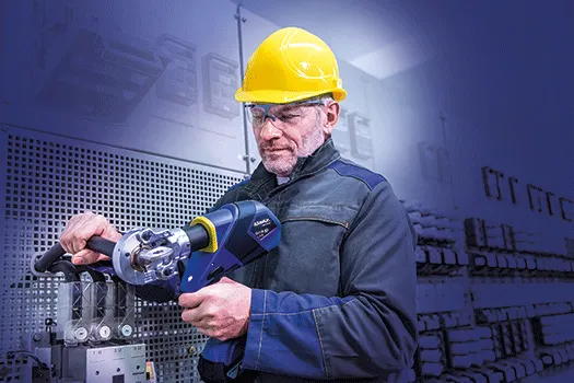 A man in a hard hat using a Klauke crimping tool