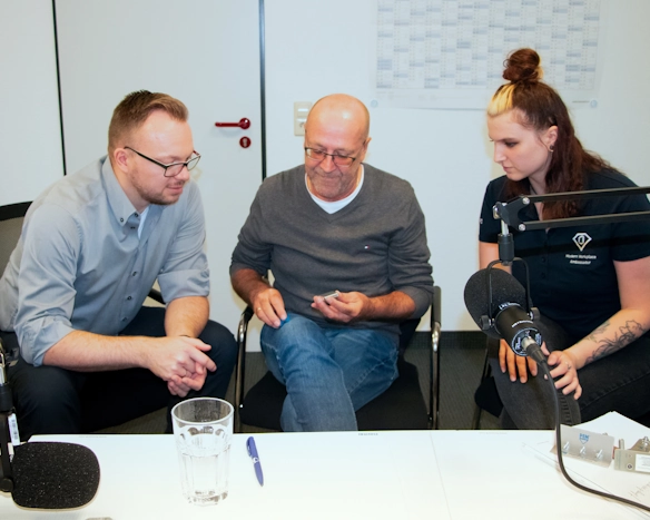 Gruppe von Fachleuten bei einer Podcast-Aufnahme engagiert in einer Diskussion