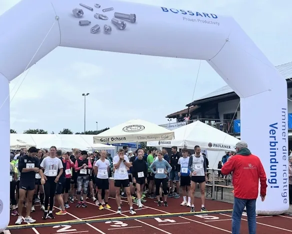 Läufer an der Startlinie eines Rennens unter einem Bossard-gebadgten Torbogen