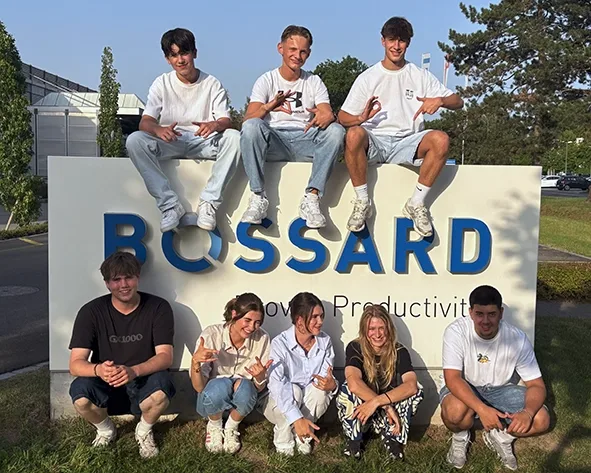 Eine Gruppe von Personen steht vor einem Schild mit der Aufschrift "Fertig".