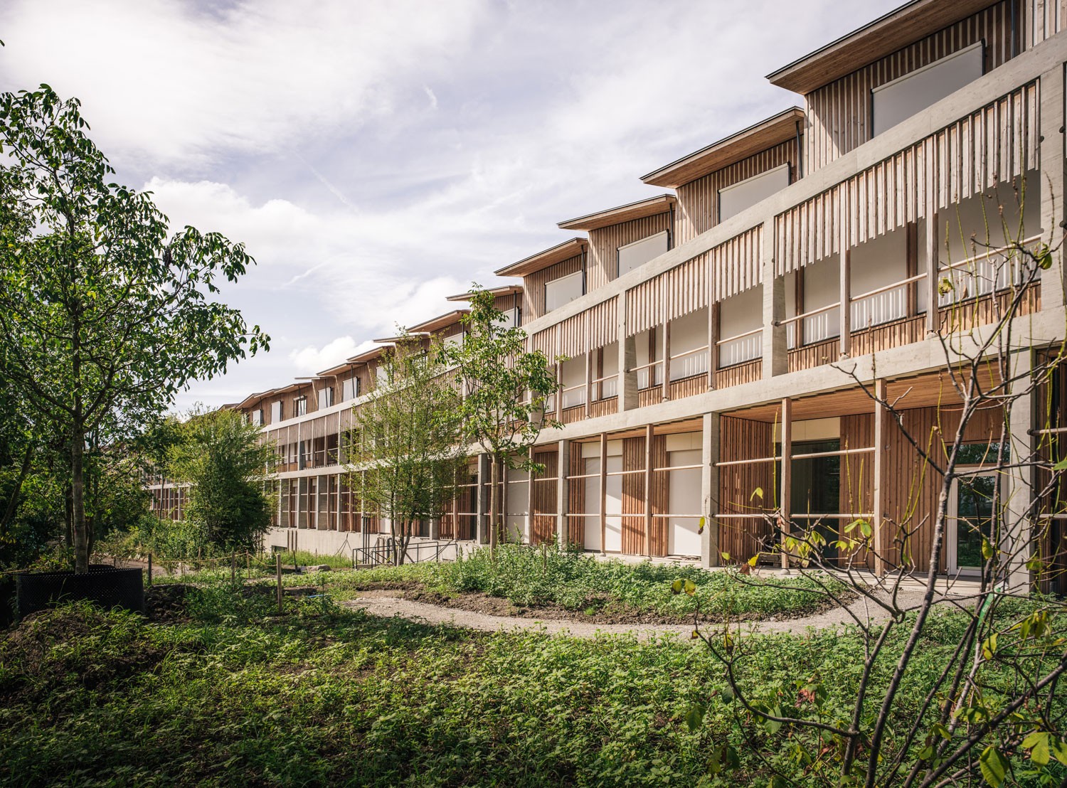 Ein Holzgebäude mit Fenstern, das das Kinderspital Zürich repräsentiert, zeigt eine moderne Holzfassade.
