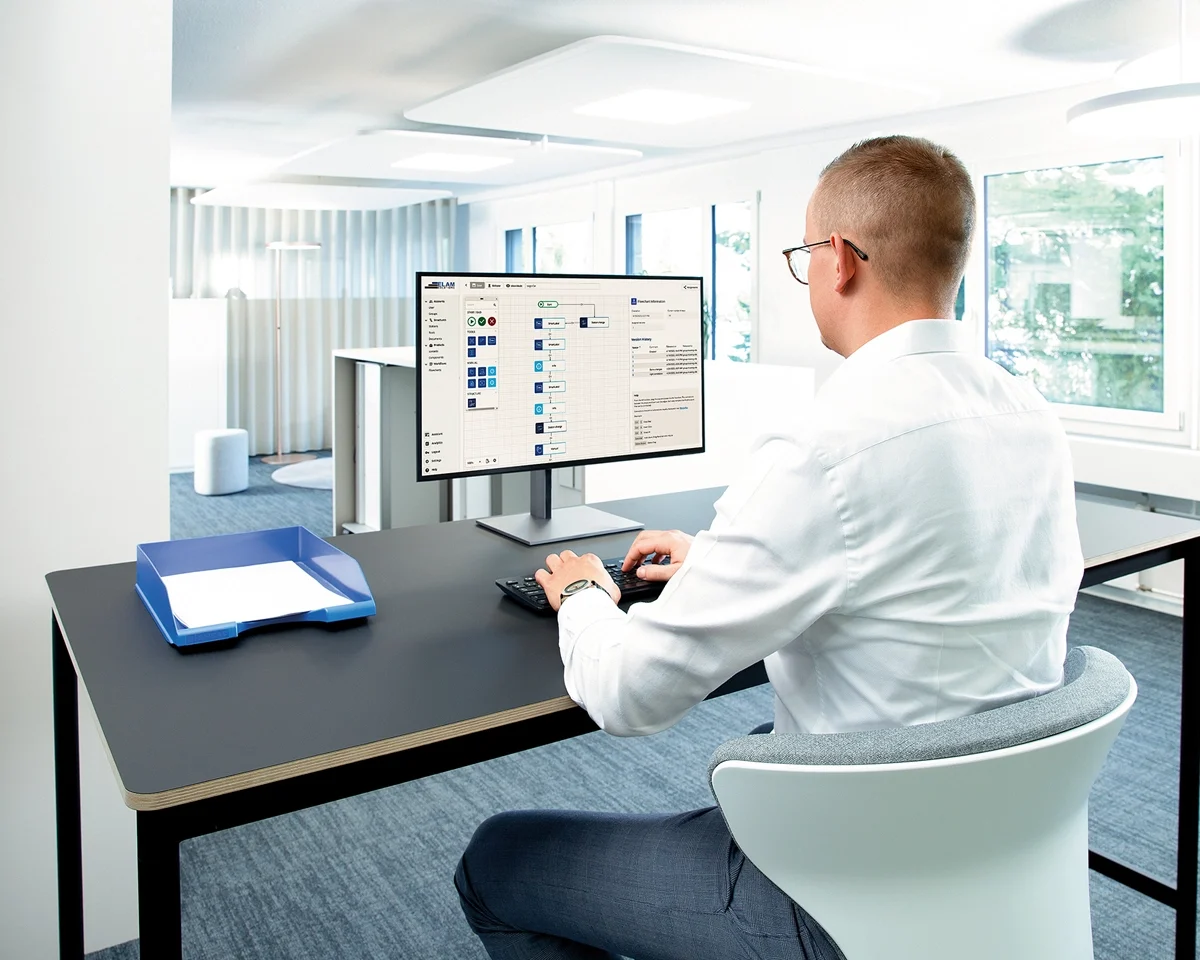 A man seated at a desk, focused on his computer screen, engaged in work.