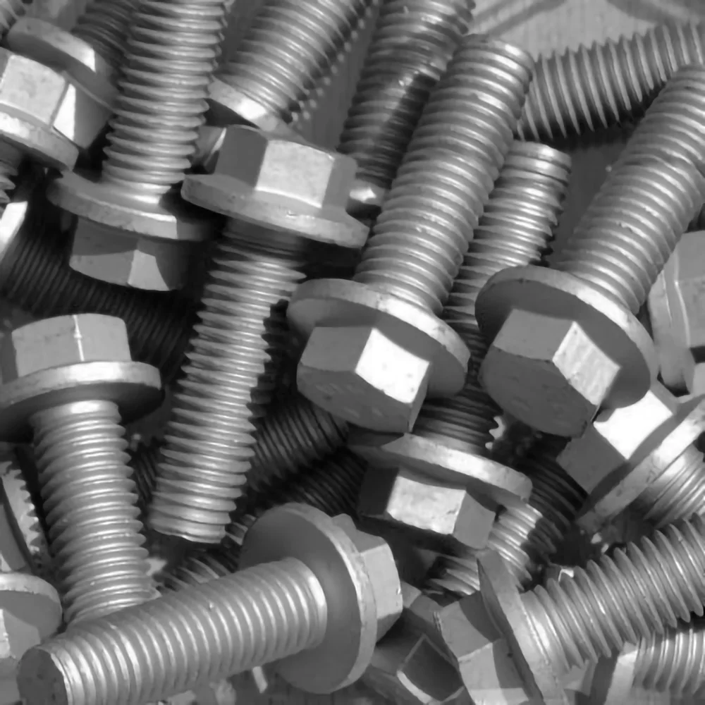 Fotografía en primer plano de múltiples pernos metálicos con cabezas hexagonales y vástagos roscados dispersos en un montón.