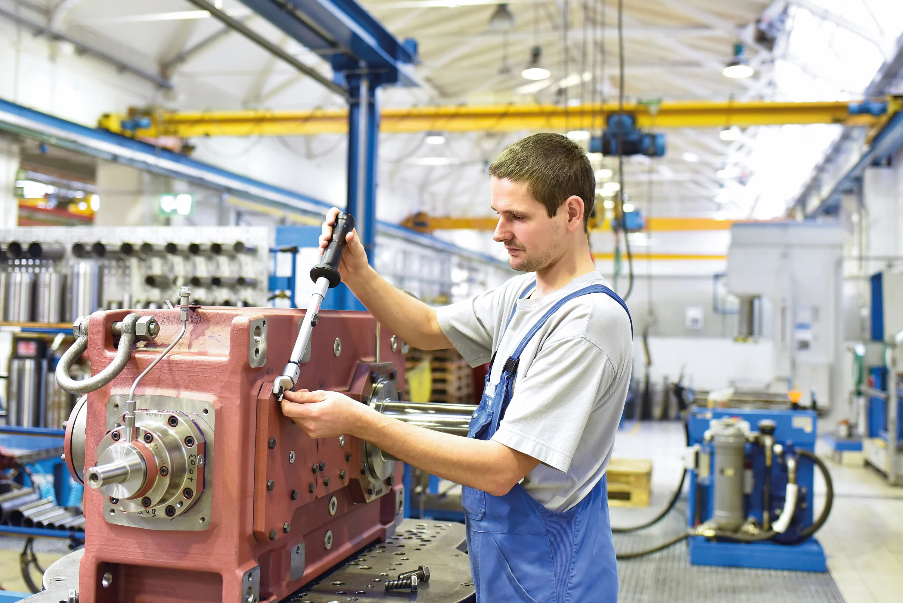 Young assembly worker in a gear manufacturing factory holding a torque wrench.