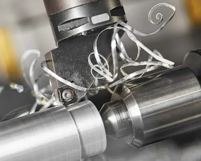 Nahaufnahme einer CNC-Drehmaschine mit Metallspänen beim Fräsen