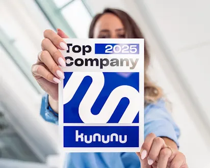 Frau hält das KUNUNU-Siegel „Top Company 2025“ in die Kamera, Auszeichnung für attraktive Arbeitgeber.