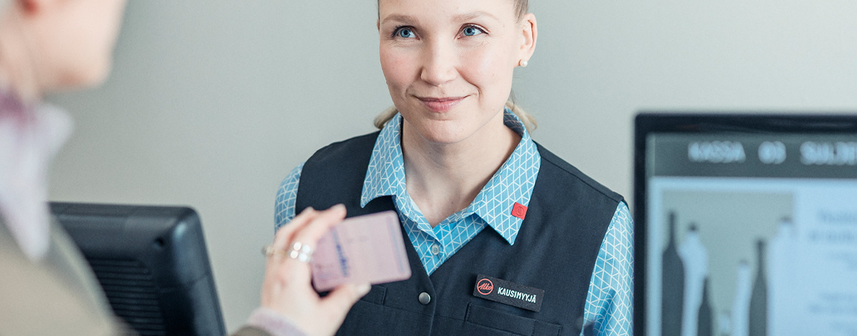 Myyjä tarkistaa asiakkaan henkilöllisyystodistuksen kassalla