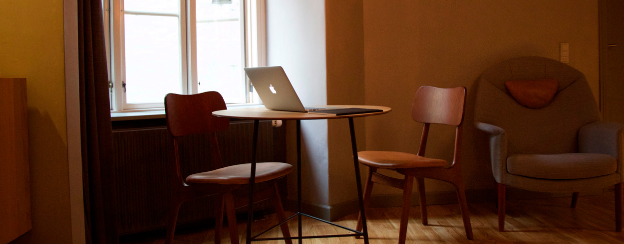 Ett runt bord med en bärbar dator på och två stolar samt en fåtölj runtom.