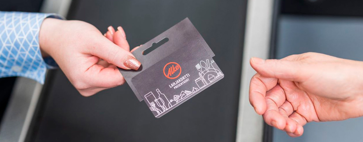 Myyjä ojentaa sähköistä lahjakorttia asiakkaan käteen