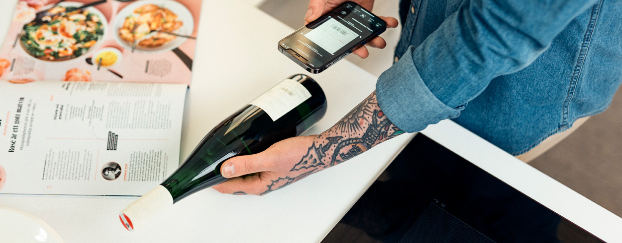 Mies skannaa viinipullon viivakoodia Alkon mobiilisovelluksella