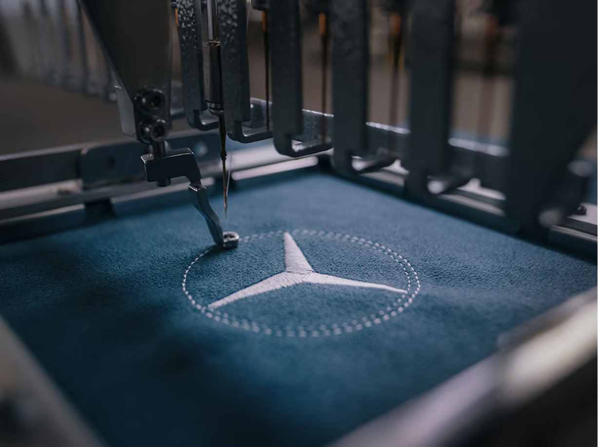 Das Mercedes-Benz Logo wird in ein Stück Wildleder gestickt