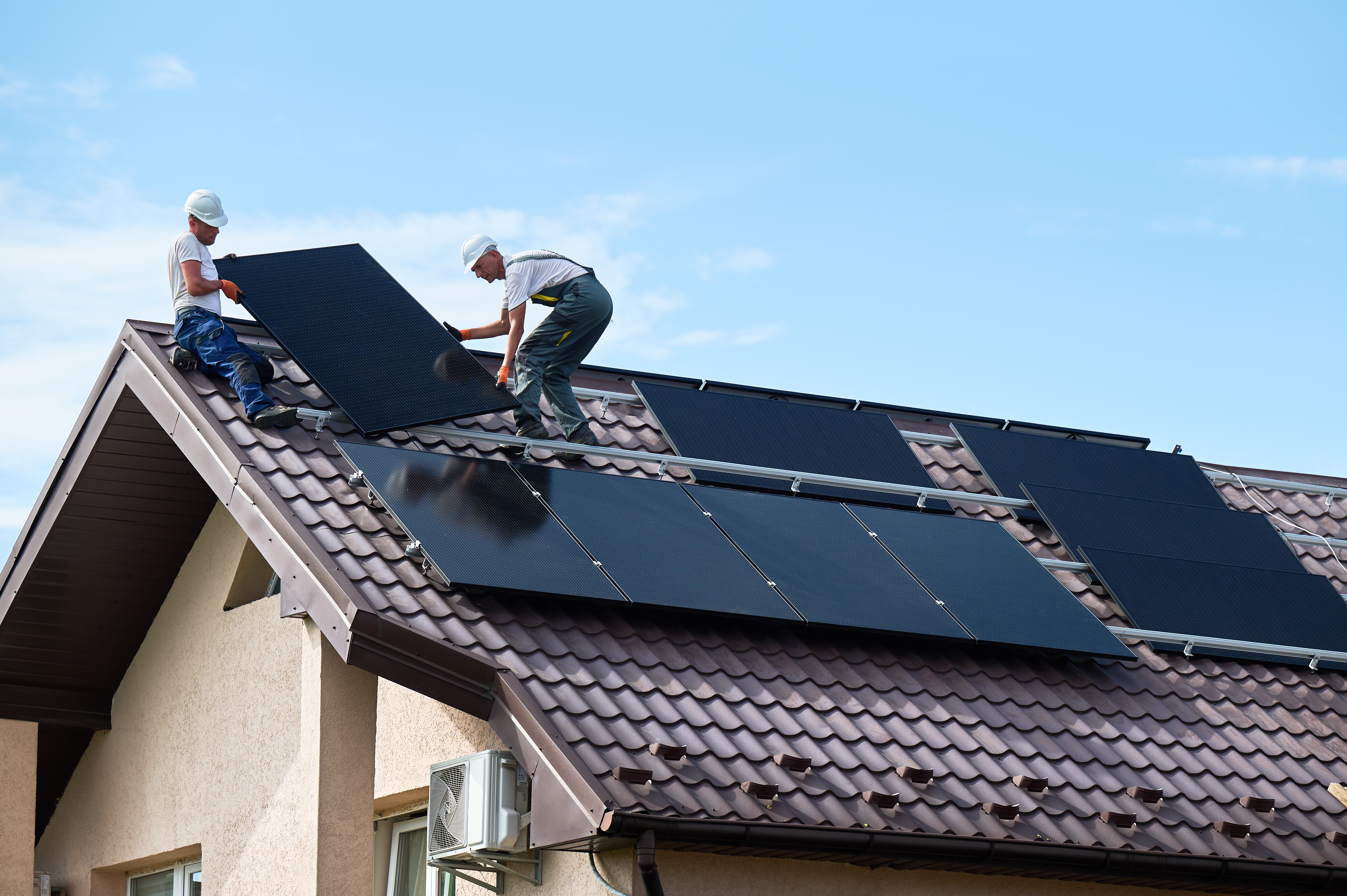 Technicians installing solar panels on a roof